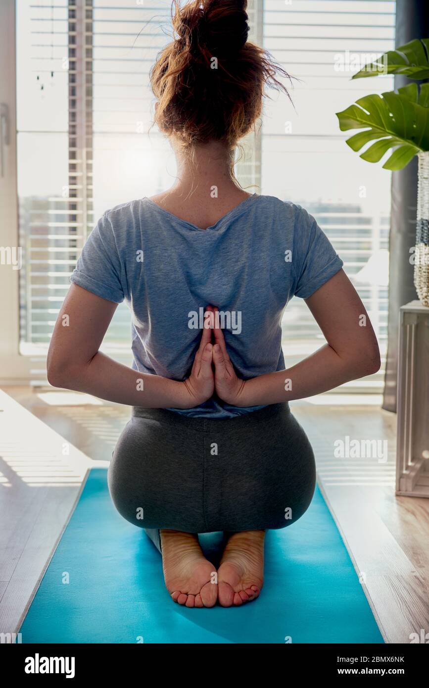 Vista posteriore della donna che fa yoga a casa Foto Stock