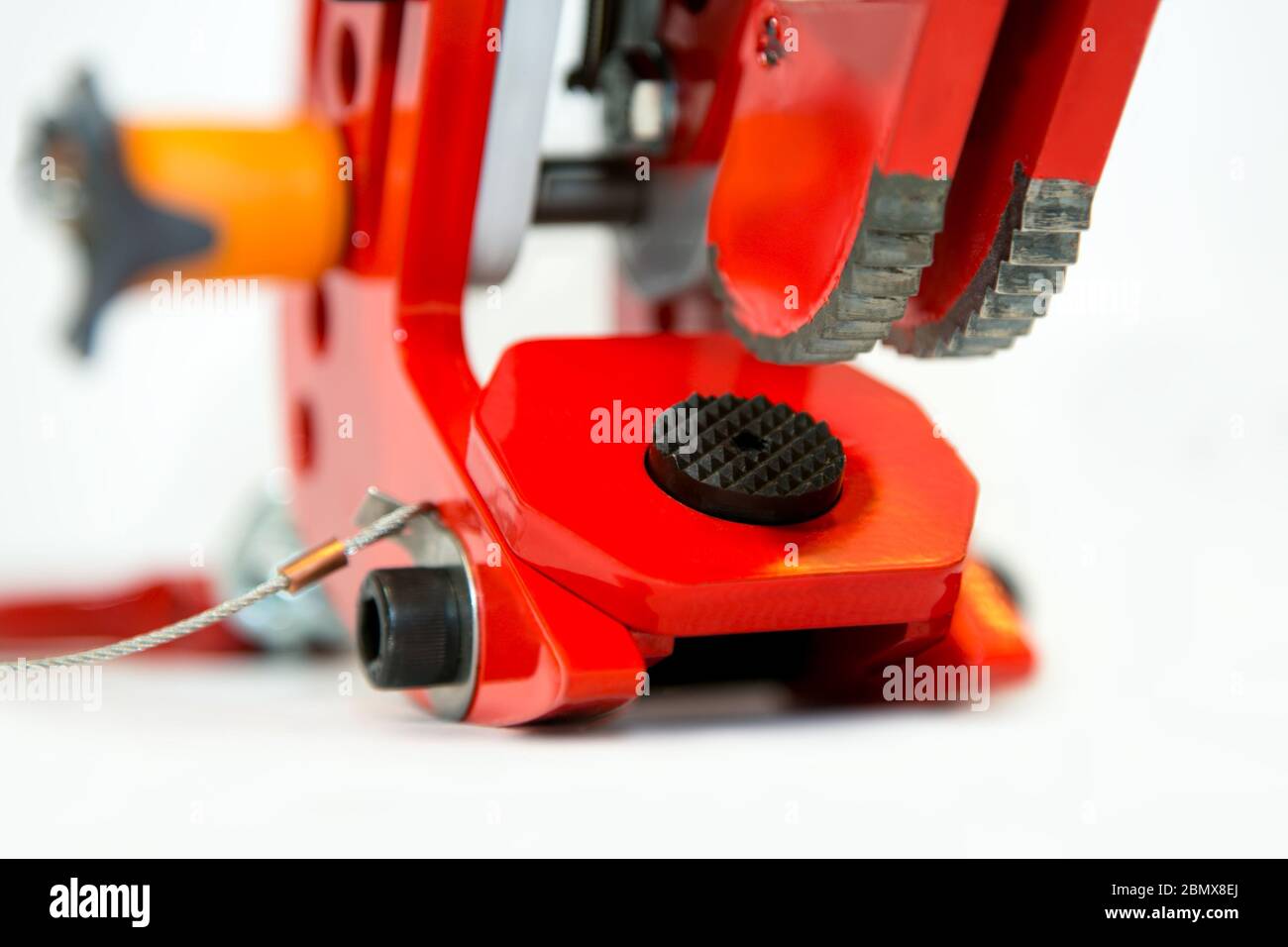 Primo piano di un meccanismo di bloccaggio rosso di un morsetto industriale di sollevamento su uno sfondo bianco Foto Stock