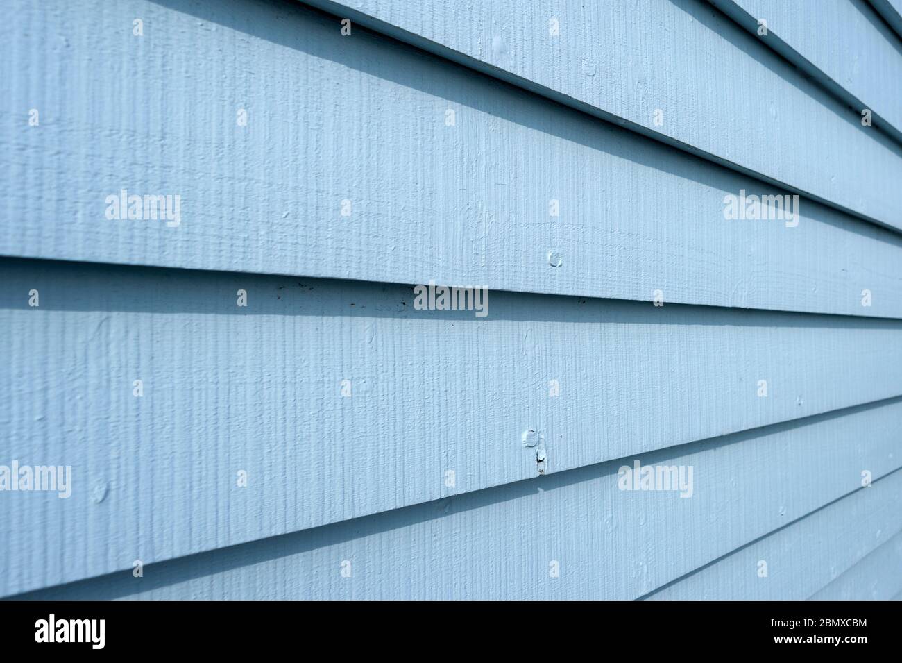 Tavole di legno verniciate blu sul lato di un edificio, primo piano. Foto Stock