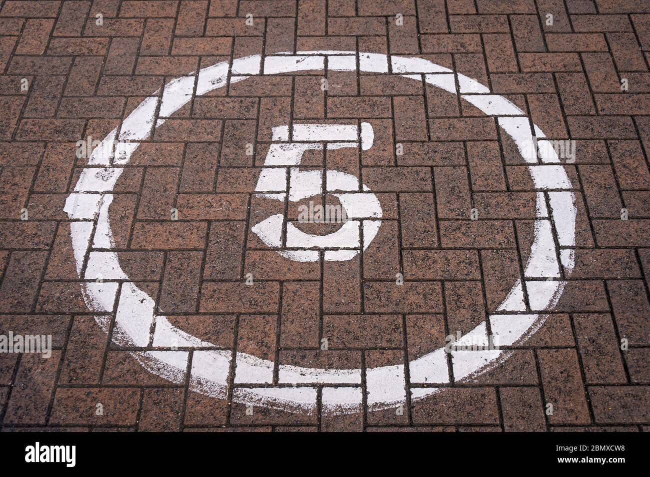 5 mph segno in un cerchio dipinto su una strada di blocco Foto Stock