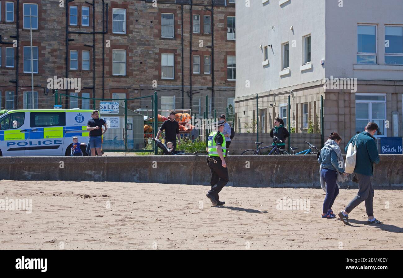 Portobello Beach, Edimburgo, Scozia, Regno Unito.11 Maggio 2020. Polizia pattuglia da quattro ufficiali amichevoli tre maschi e una femmina sul mare abbastanza tranquillo, Avendo chiacchierato con le poche persone che erano seduti sulla spiaggia sabbiosa o sul muro della passeggiata consigliando che potrebbero contrarre il Coronavirus da superfici che toccano mentre sono al mare e consigliando loro di muoversi lungo e prendere il loro excercise permesso mentre fuori e circa. Credit: Arch White/Alamy Live News Foto Stock