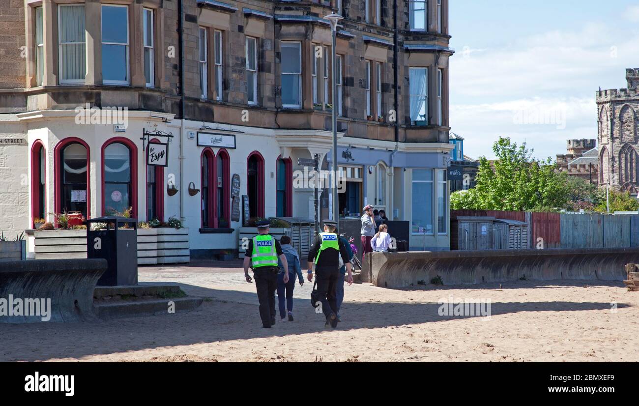 Portobello Beach, Edimburgo, Scozia, Regno Unito.11 Maggio 2020. Polizia pattuglia da quattro ufficiali amichevoli tre maschi e una femmina sul mare abbastanza tranquillo, Avendo chiacchierato con le poche persone che erano seduti sulla spiaggia sabbiosa o sul muro della passeggiata consigliando che potrebbero contrarre il Coronavirus da superfici che toccano mentre sono al mare e consigliando loro di muoversi lungo e prendere il loro excercise permesso mentre fuori e circa. Credit: Arch White/Alamy Live News Foto Stock