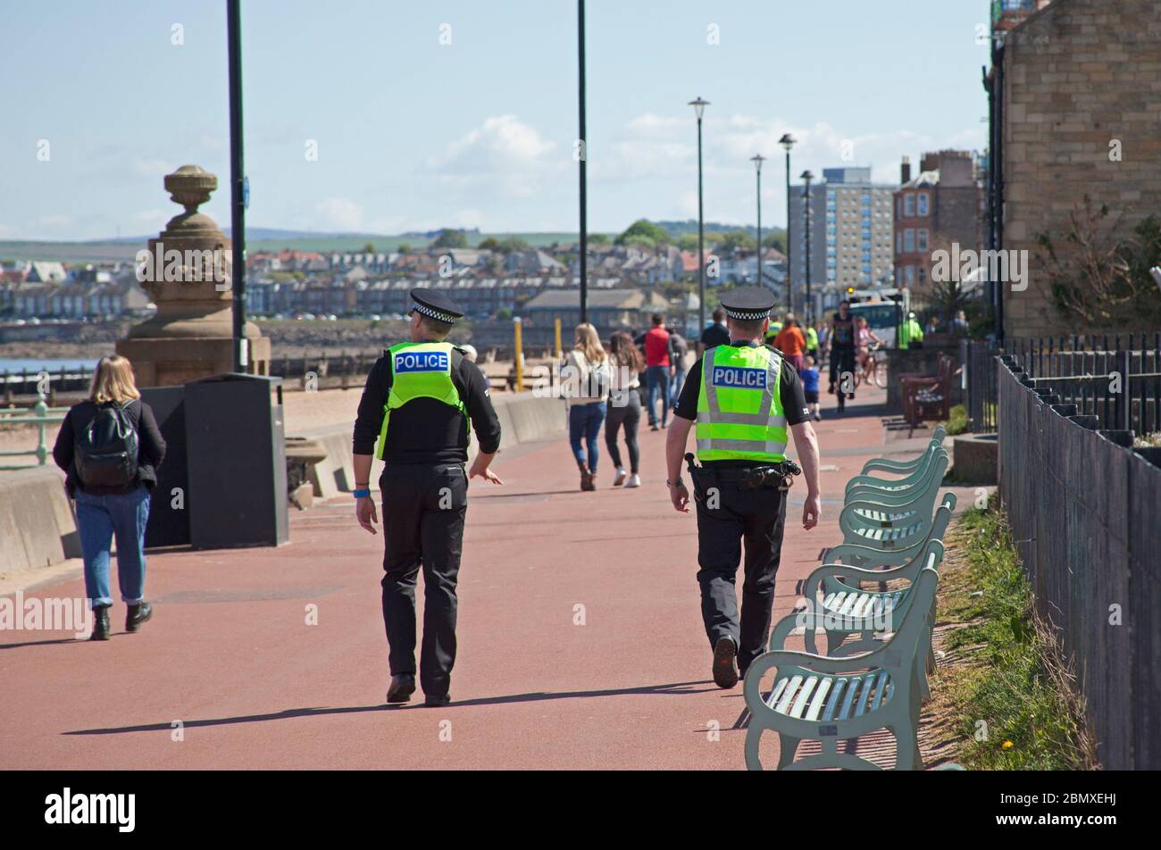 Portobello Beach, Edimburgo, Scozia, Regno Unito.11 Maggio 2020. Polizia pattuglia da quattro ufficiali amichevoli tre maschi e una femmina sul mare abbastanza tranquillo, Avendo chiacchierato con le poche persone che erano seduti sulla spiaggia sabbiosa o sul muro della passeggiata consigliando che potrebbero contrarre il Coronavirus da superfici che toccano mentre sono al mare e consigliando loro di muoversi lungo e prendere il loro excercise permesso mentre fuori e circa. Credit: Arch White/Alamy Live News Foto Stock