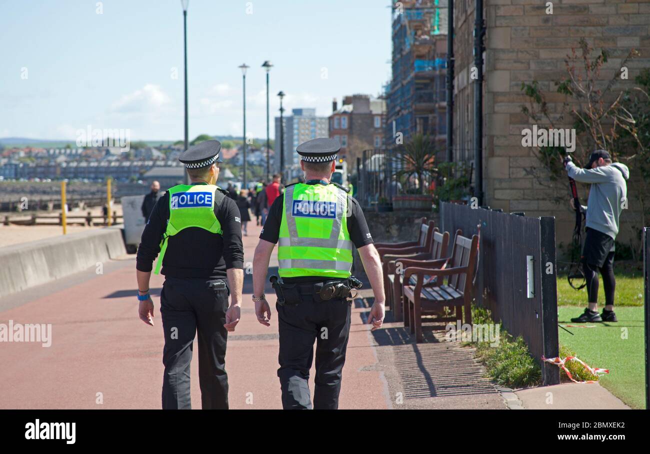 Portobello Beach, Edimburgo, Scozia, Regno Unito.11 Maggio 2020. Polizia pattuglia da quattro ufficiali amichevoli tre maschi e una femmina sul mare abbastanza tranquillo, Avendo chiacchierato con le poche persone che erano seduti sulla spiaggia sabbiosa o sul muro della passeggiata consigliando che potrebbero contrarre il Coronavirus da superfici che toccano mentre sono al mare e consigliando loro di muoversi lungo e prendere il loro excercise permesso mentre fuori e circa. Credit: Arch White/Alamy Live News Foto Stock