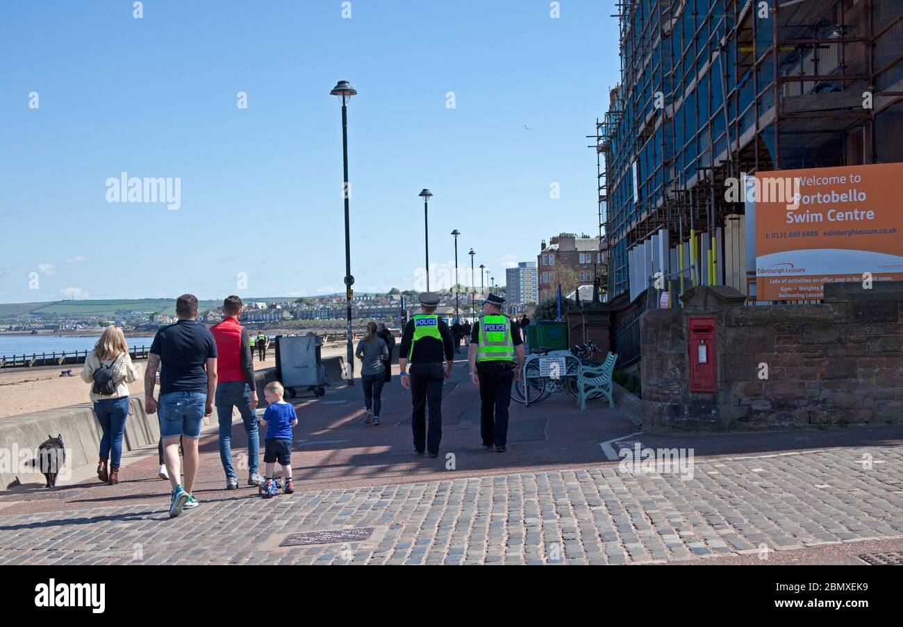 Portobello Beach, Edimburgo, Scozia, Regno Unito.11 Maggio 2020. Polizia pattuglia da quattro ufficiali amichevoli tre maschi e una femmina sul mare abbastanza tranquillo, Avendo chiacchierato con le poche persone che erano seduti sulla spiaggia sabbiosa o sul muro della passeggiata consigliando che potrebbero contrarre il Coronavirus da superfici che toccano mentre sono al mare e consigliando loro di muoversi lungo e prendere il loro excercise permesso mentre fuori e circa. Credit: Arch White/Alamy Live News Foto Stock