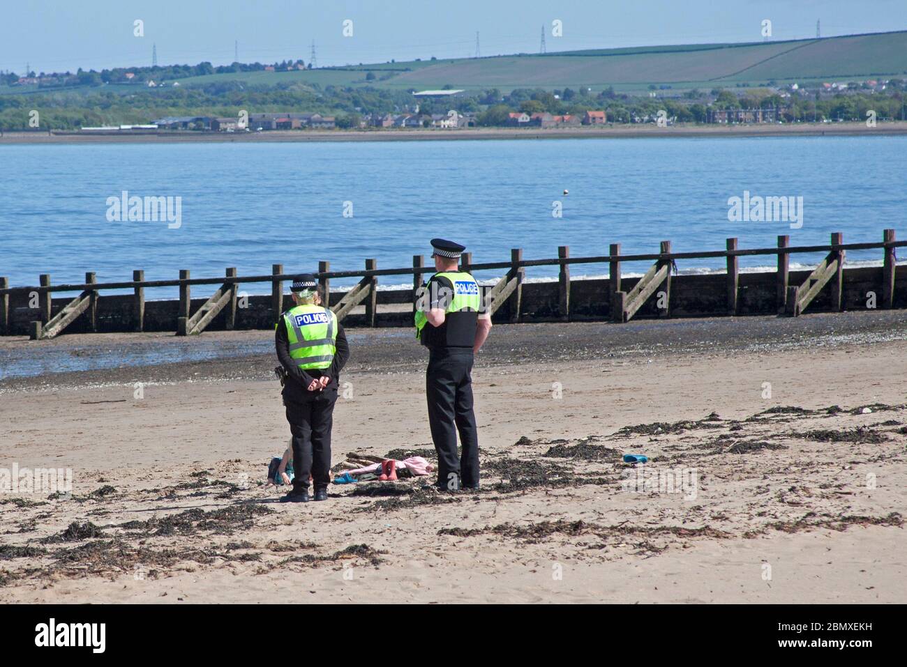 Portobello Beach, Edimburgo, Scozia, Regno Unito.11 Maggio 2020. Polizia pattuglia da quattro ufficiali amichevoli tre maschi e una femmina sul mare abbastanza tranquillo, Avendo chiacchierato con le poche persone che erano seduti sulla spiaggia sabbiosa o sul muro della passeggiata consigliando che potrebbero contrarre il Coronavirus da superfici che toccano mentre sono al mare e consigliando loro di muoversi lungo e prendere il loro excercise permesso mentre fuori e circa. Credit: Arch White/Alamy Live News Foto Stock