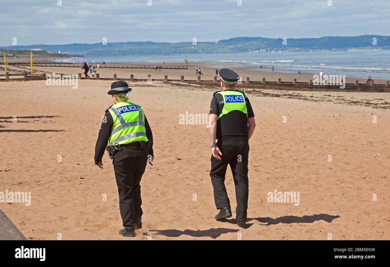 Portobello Beach, Edimburgo, Scozia, Regno Unito.11 Maggio 2020. Polizia pattuglia da quattro ufficiali amichevoli tre maschi e una femmina sul mare abbastanza tranquillo, Avendo chiacchierato con le poche persone che erano seduti sulla spiaggia sabbiosa o sul muro della passeggiata consigliando che potrebbero contrarre il Coronavirus da superfici che toccano mentre sono al mare e consigliando loro di muoversi lungo e prendere il loro excercise permesso mentre fuori e circa. Credit: Arch White/Alamy Live News Foto Stock