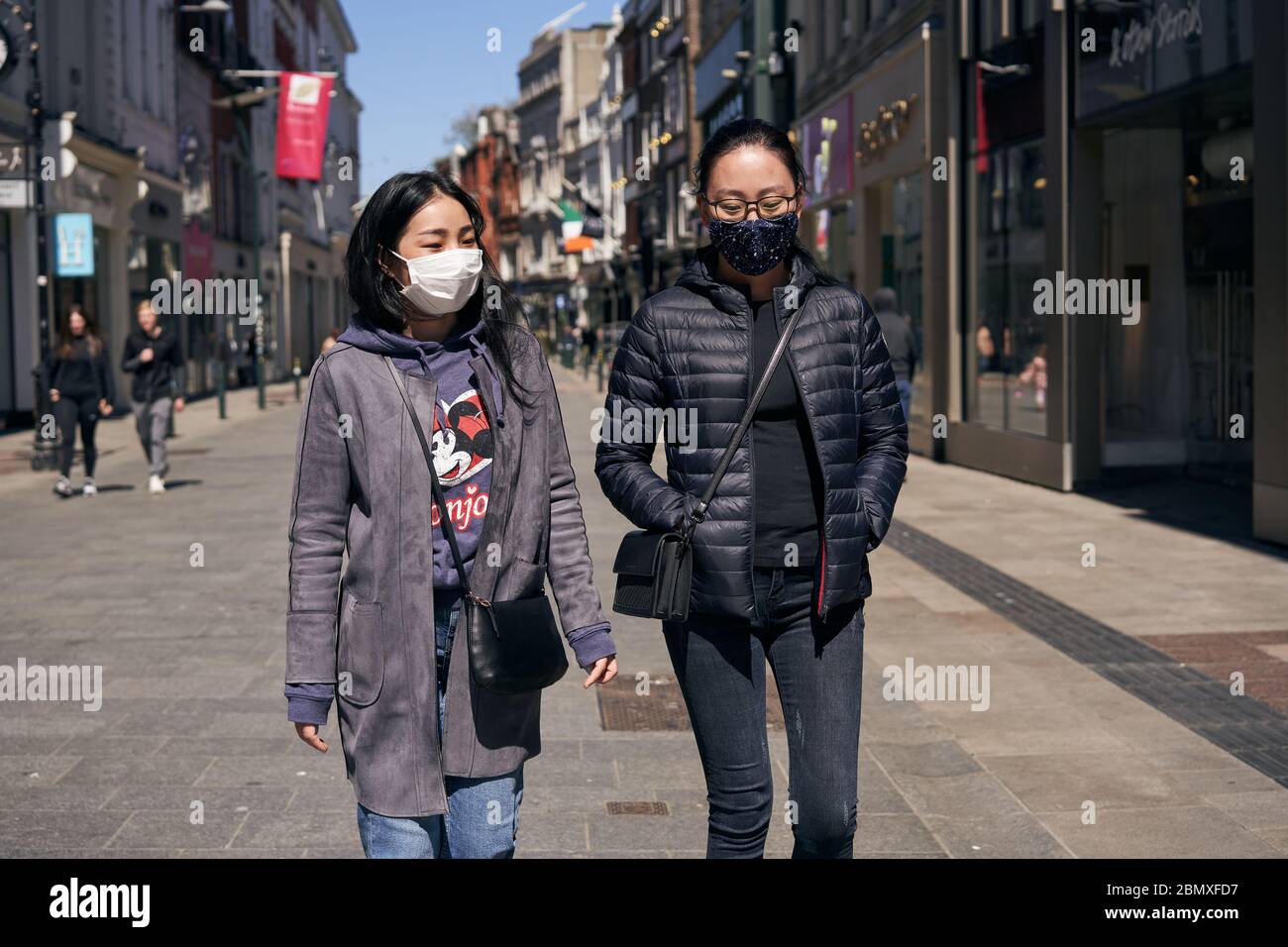Due ragazze che indossano maschere facciali durante le passeggiate pandemiche di Coronavirus lungo Grafton Street nella città di Dublino, Irlanda. Foto Stock