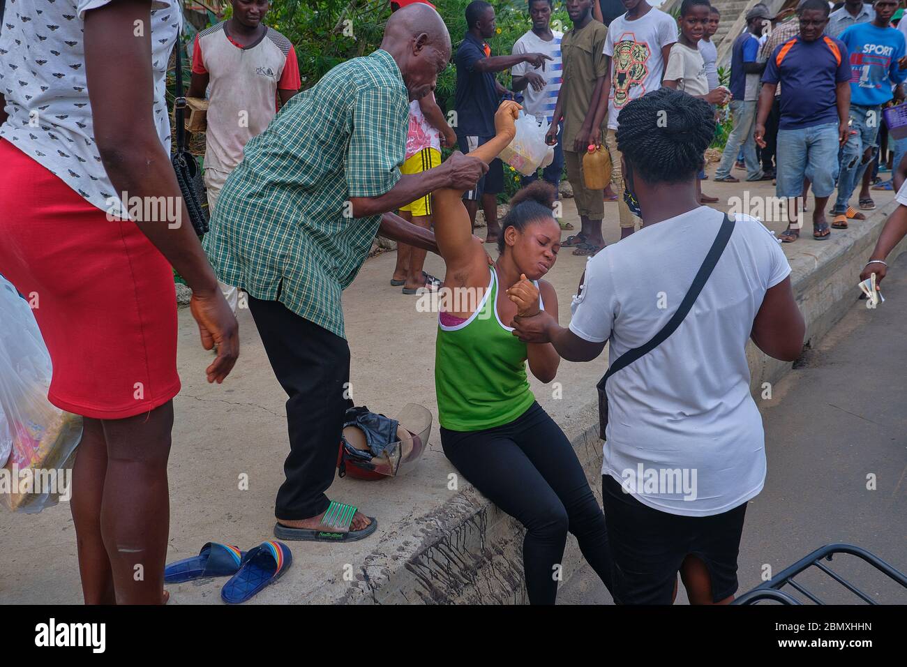 La gente aiuta una vittima di un incidente stradale a Lagos, in Nigeria. Foto Stock
