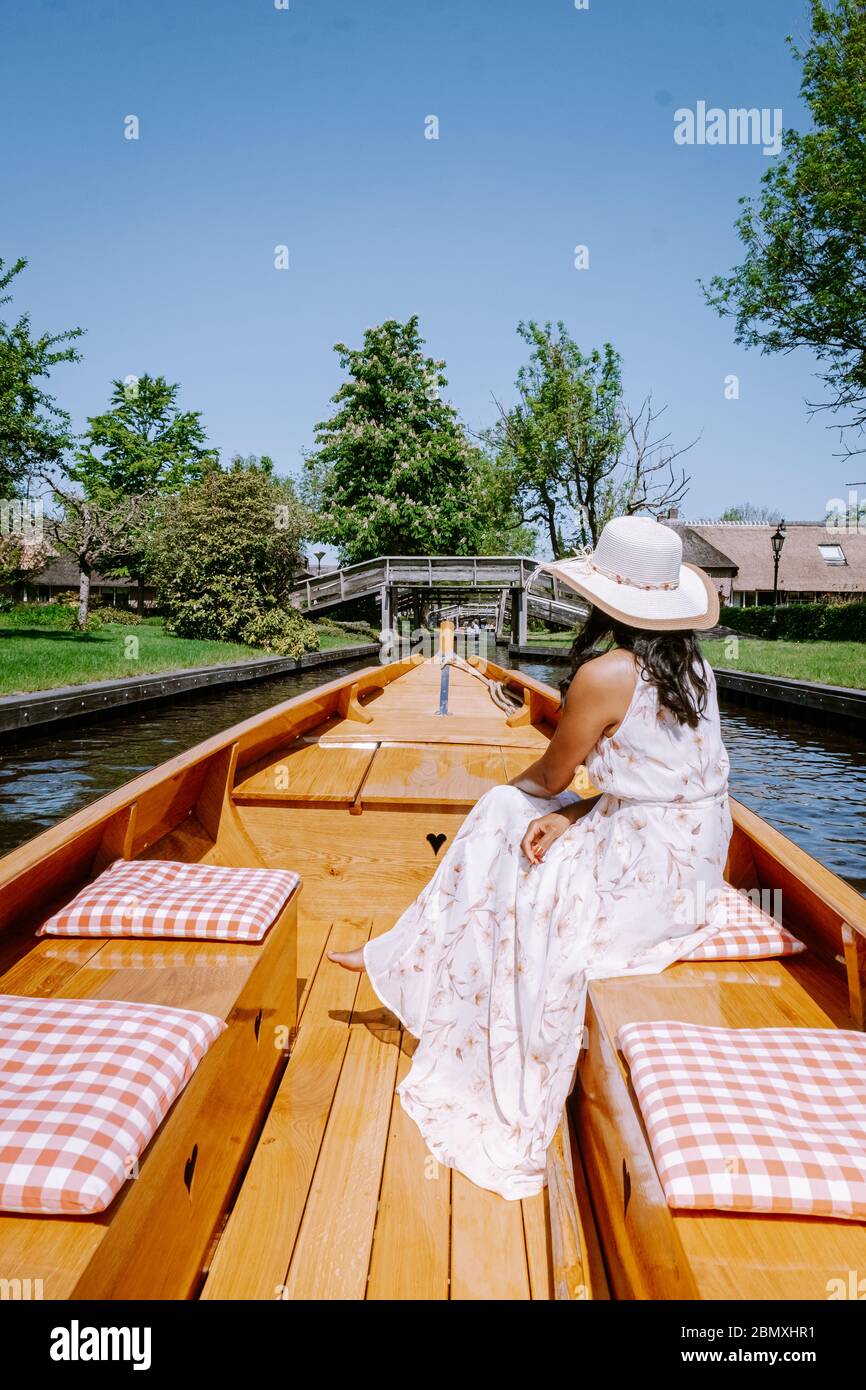 Giethoorn Olanda donna visitare il villaggio con una barca, vista del famoso villaggio con canali e case rustiche tetto di paglia in zona fattoria su un caldo Foto Stock