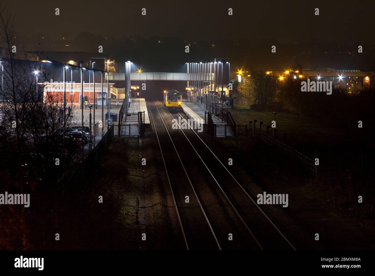 Treno Northern di classe 142 per il pacer che chiama alla stazione ferroviaria di Buckshaw parkway sulla linea ferroviaria da Bolton a Preston di notte Foto Stock