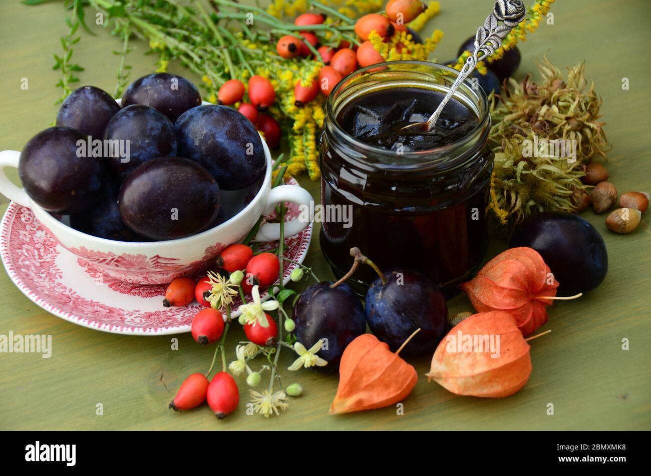 Ancora vita con prugne e una confettura di prugne di vetro. Foto Stock