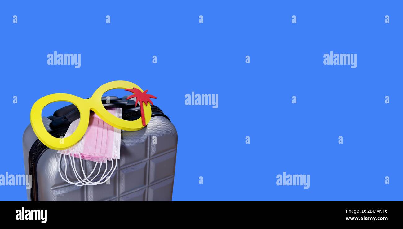 COVID-19 maschera medica e valigetta da viaggio in viaggio durante l'epidemia di Coronavirus. Pandemico concetto di viaggio. Foto Stock