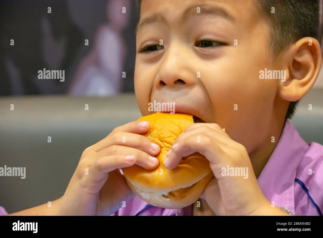 Hamburger pesce in mano asia ragazzo che tiene il mangiare. Foto Stock
