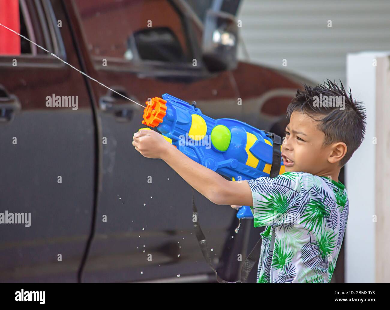 Ragazzo asiatico in possesso di una pistola ad acqua giocare Songkran festival tailandese o il nuovo anno in Thailandia. Foto Stock