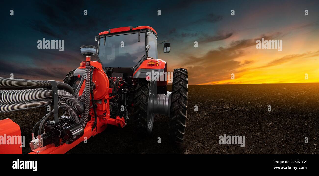 Trattore rosso con seminatrice su un campo agricolo Foto Stock