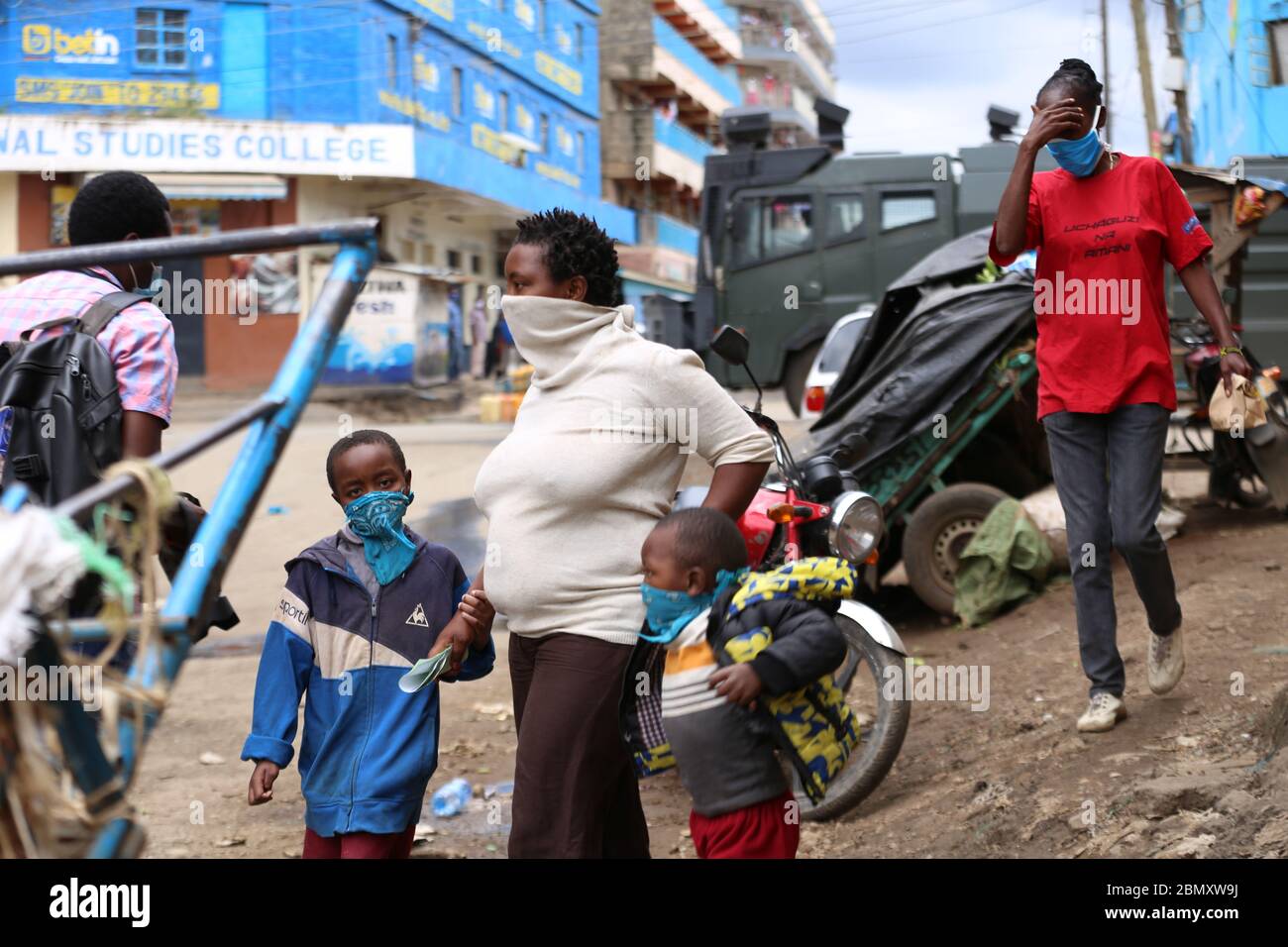 I residenti camminano davanti ad un veicolo armato della polizia a Eastleigh durante la protesta.i residenti di Eastleigh hanno preso alla strada per protestare la restrizione del movimento nella zona a causa del caso diffuso di Covid-19 all'interno dell'area residenziale e hanno fatto appello al governo per fornire loro il cibo di soccorso. Il Kenya ha confermato 672 casi di Covid-19 e 32 morti. Foto Stock