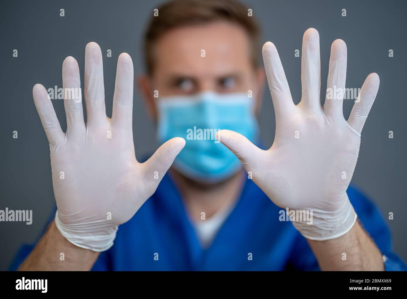 Focolaio COVID-19. Aiuto per fermare la diffusione del virus. Medico o infermiere che indossa maschera chirurgica facciale e guanti DPI che mostrano le mani in STOP gesture. Soggiorno s Foto Stock