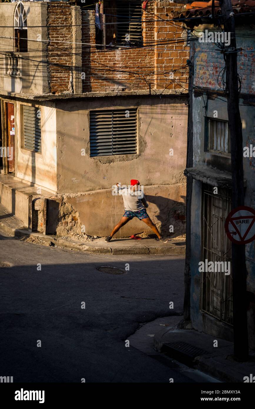 Uomo che lancia il baseball in un quartiere di classe operaia, Santiago de Cuba, Cuba Foto Stock