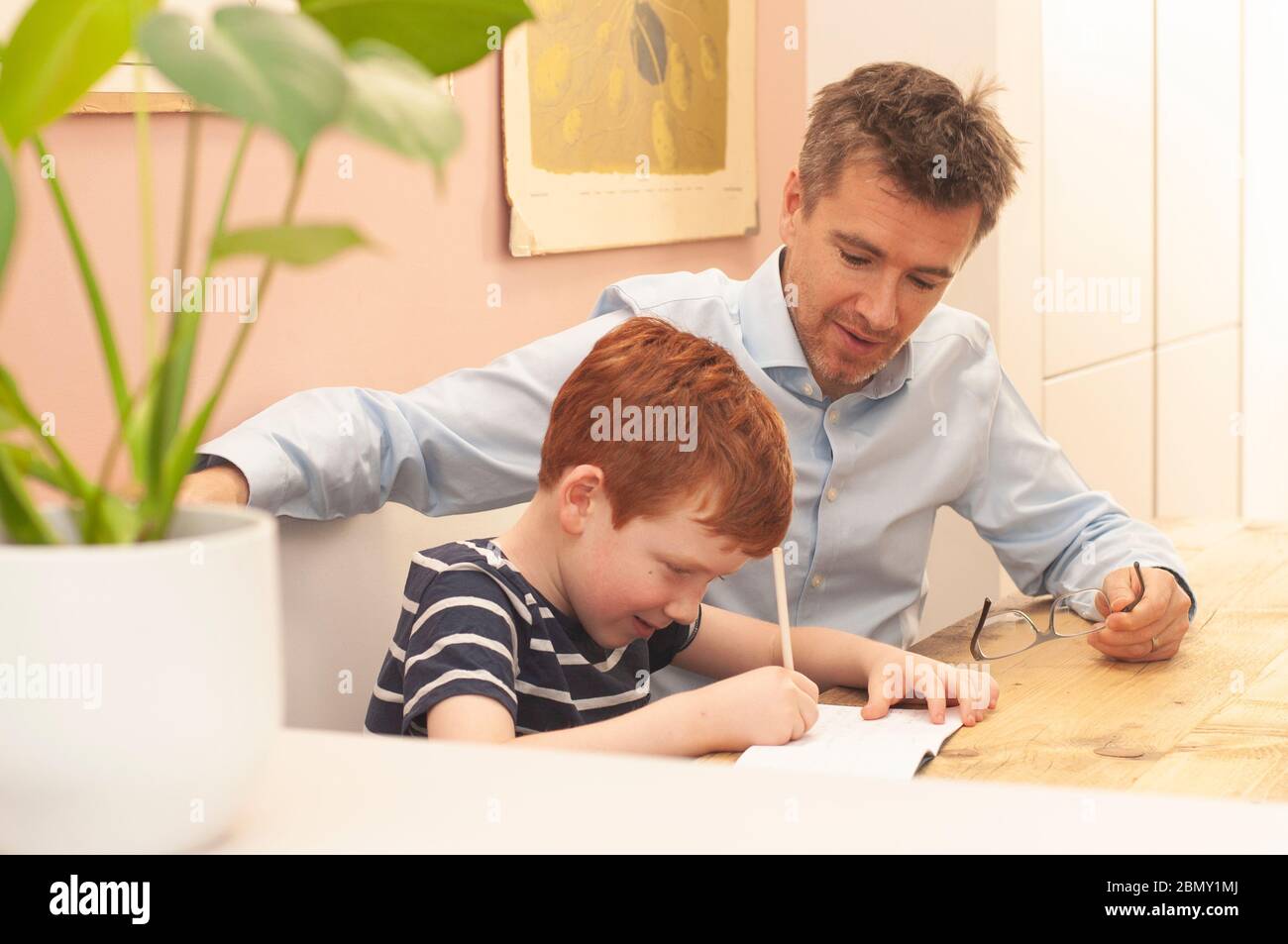 Papà che aiuta il ragazzo pre-teen con il suo lavoro scolastico a casa durante la homeschooling dovuto il blocco del coronavirus. Formato orizzontale. Foto Stock