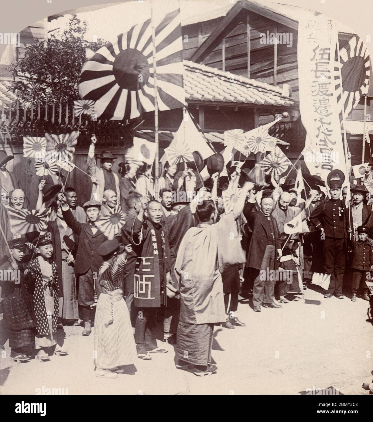 [ 1900s Japan - Russo-Japanese War ] - Famiglia e amici che salutano un giovane che va in guerra durante la guerra russo-giapponese (1904-1905), 1904 (Meiji 37). Stanno sventolando le bandiere del sole (旭日旗, Kyokujitsu-ki). La bandiera è ancora utilizzata come segnale navale del Giappone (軍艦旗, Gunkanki). Foto Stock