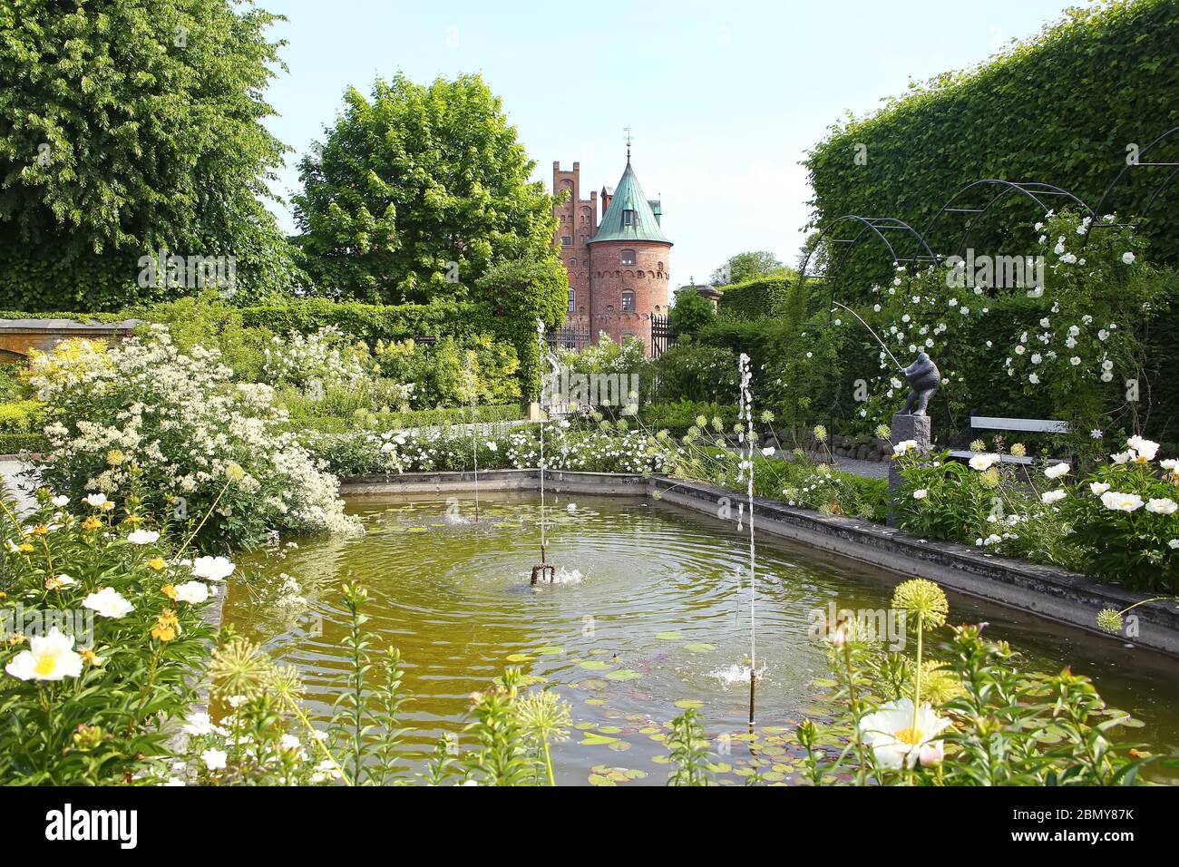 Tradizionale giardino pubblico formale, in fiore in estate con un lago e piccole fontane in primo piano, situato vicino Kvaerndrup, nel sud del Foto Stock