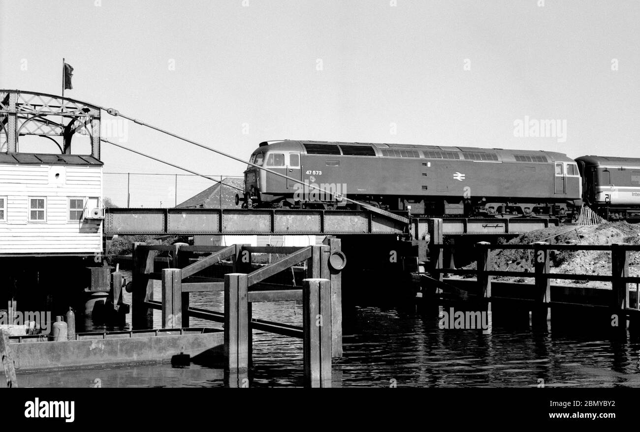 Locomotiva diesel di classe 47 n. 47573 che attraversa il ponte di oscillazione di Trowse, Norwich, Regno Unito. 30 maggio 1985. Foto Stock