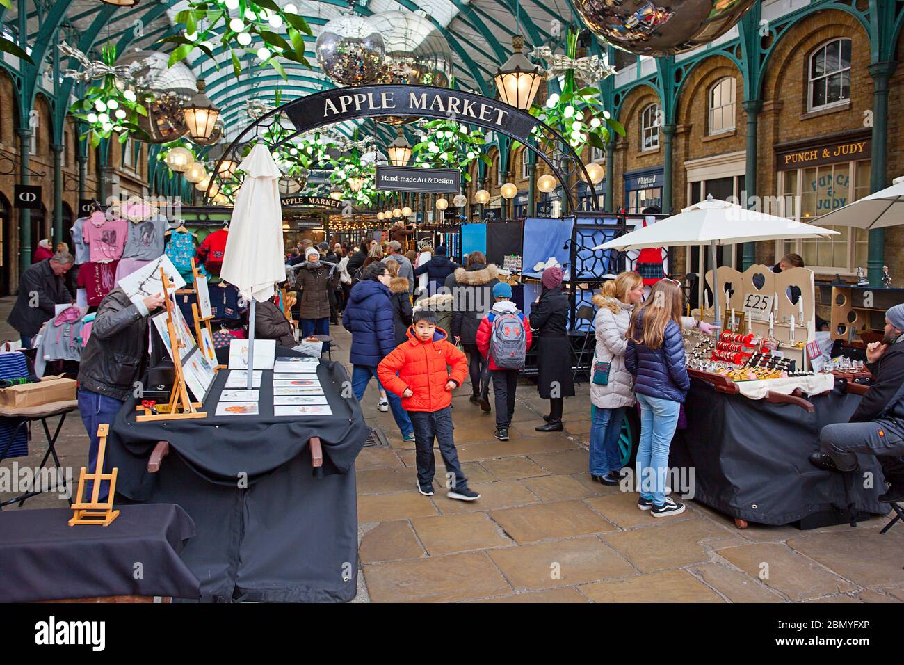 Persone che navigano merci in vendita presso Apple Market, Covent Garden, Londra Foto Stock