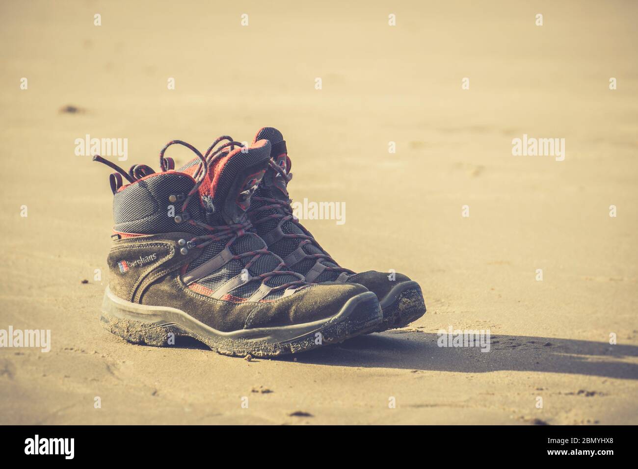 Chiudi coppia di stivali da uomo isolati sulla sabbia, a Newborough Beach, Anglesey, Regno Unito. Vacanze/vacanze estive in Galles.spazio copia. Foto Stock