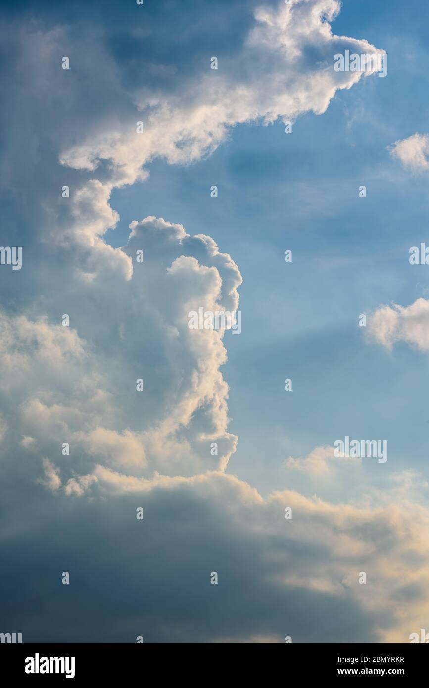 cielo blu pastello con paesaggi e raggi di luce, formato ritratto con spazio di copia sul lato destro Foto Stock