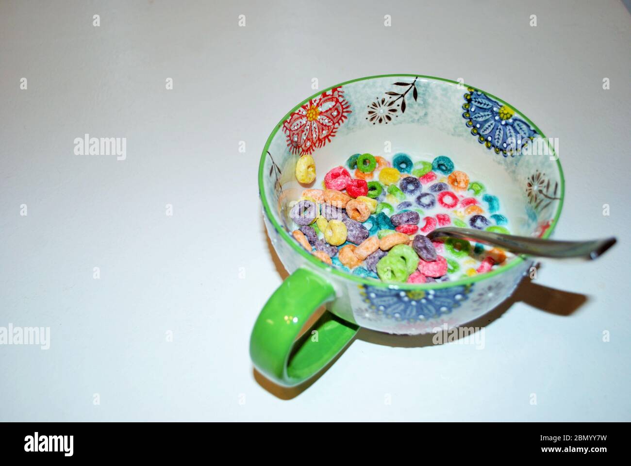 Primo piano di una ciotola piena di frutta aromatizzata loops di zucchero pronto a mangiare cereali per la colazione con un cucchiaio che sporge Foto Stock