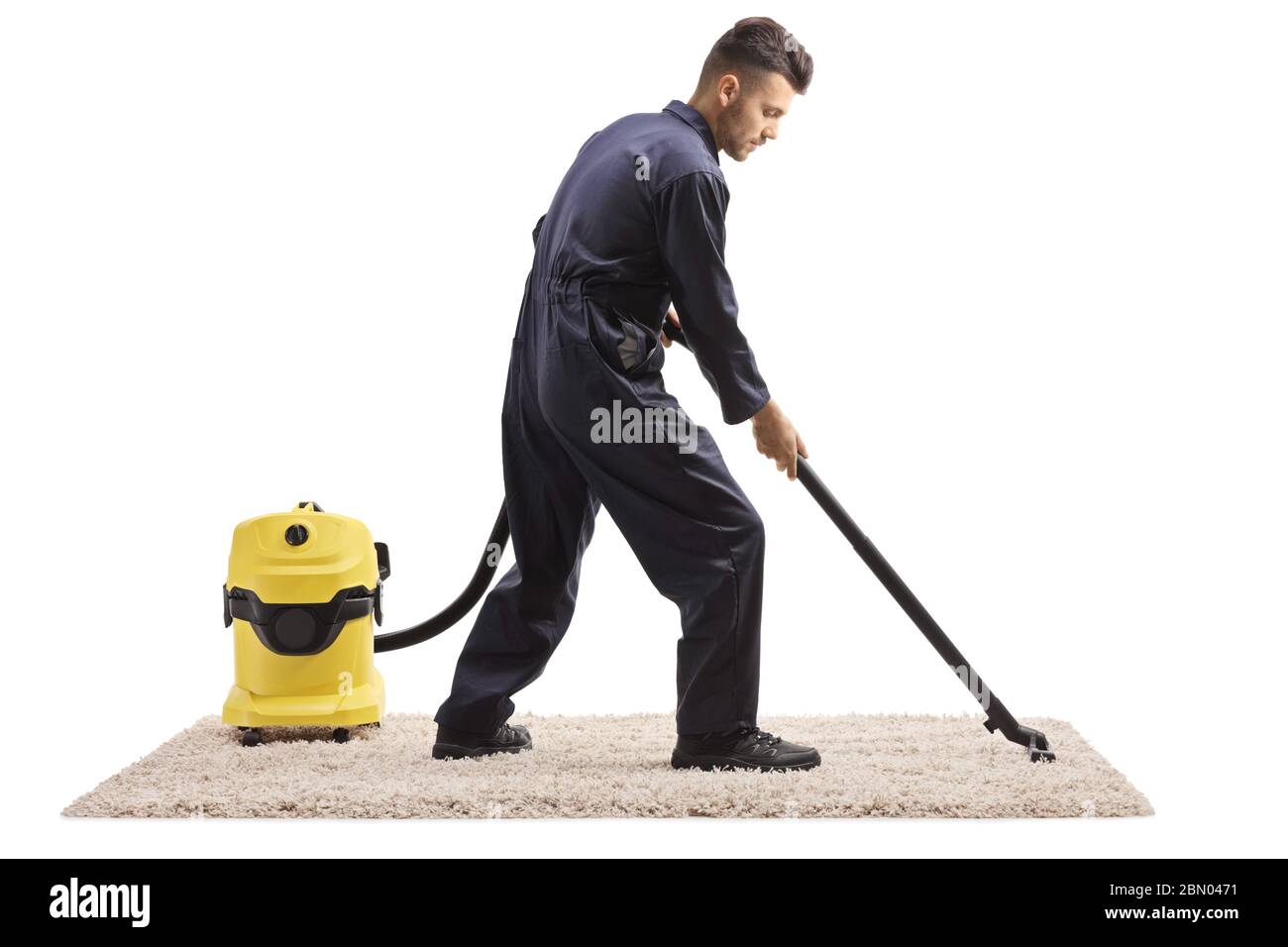 Scatto a tutta lunghezza di un lavoratore maschile in uniforme con un aspirapolvere che collega un tappeto isolato su sfondo bianco Foto Stock