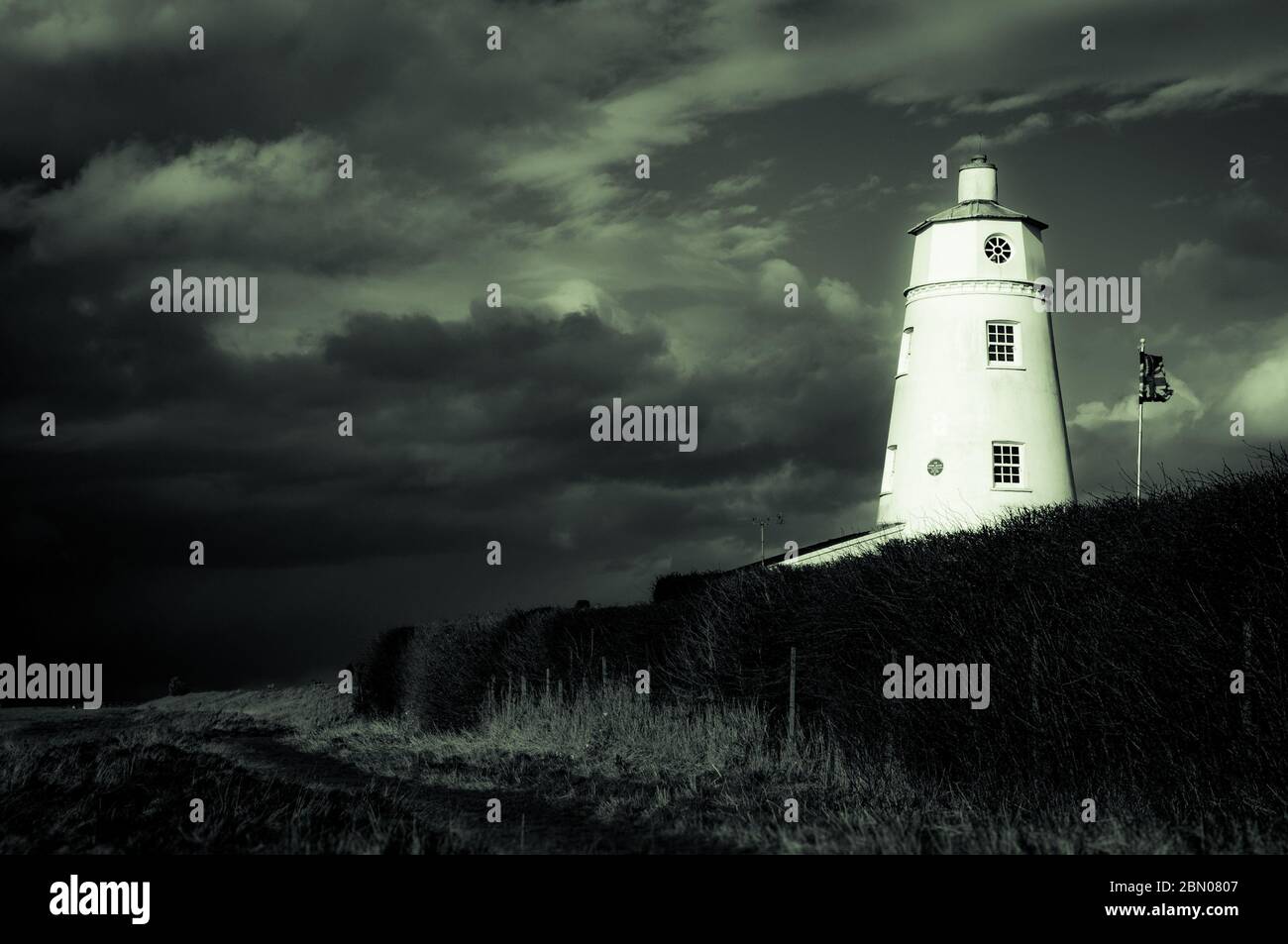 Luce del sole invernale che cade sul faro di East Bank famoso per l'oca della neve, contro un cielo tempestoso in Sutton Bridge, fiume Nene, Spalding, Lincolnshire Foto Stock