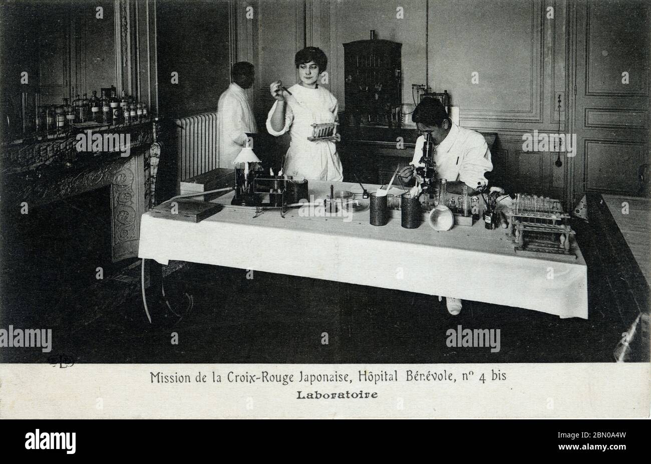 [ 1910s Giappone - Missione della Croce Rossa della prima Guerra Mondiale, Parigi ] – un medico giapponese controlla un esemplare al microscopio presso il laboratorio di una missione della Società della Croce Rossa Giapponese presso l'ospedale temporaneo Hôpital Bénévole 4 bis, a Parigi, durante la prima Guerra Mondiale. L'ospedale si trova all'Astoria Hotel in rue de Presbourg. La Croce Rossa Giapponese la gestì dal 15 febbraio 1915 (Taisho 4) al 1 luglio 1916 (Taisho 5). Testo originale: Mission de la Croix-Rouge Japonaise, Hôpital Bénévole, no 4 bis: Laboratoire cartolina d'epoca del XX secolo. Foto Stock