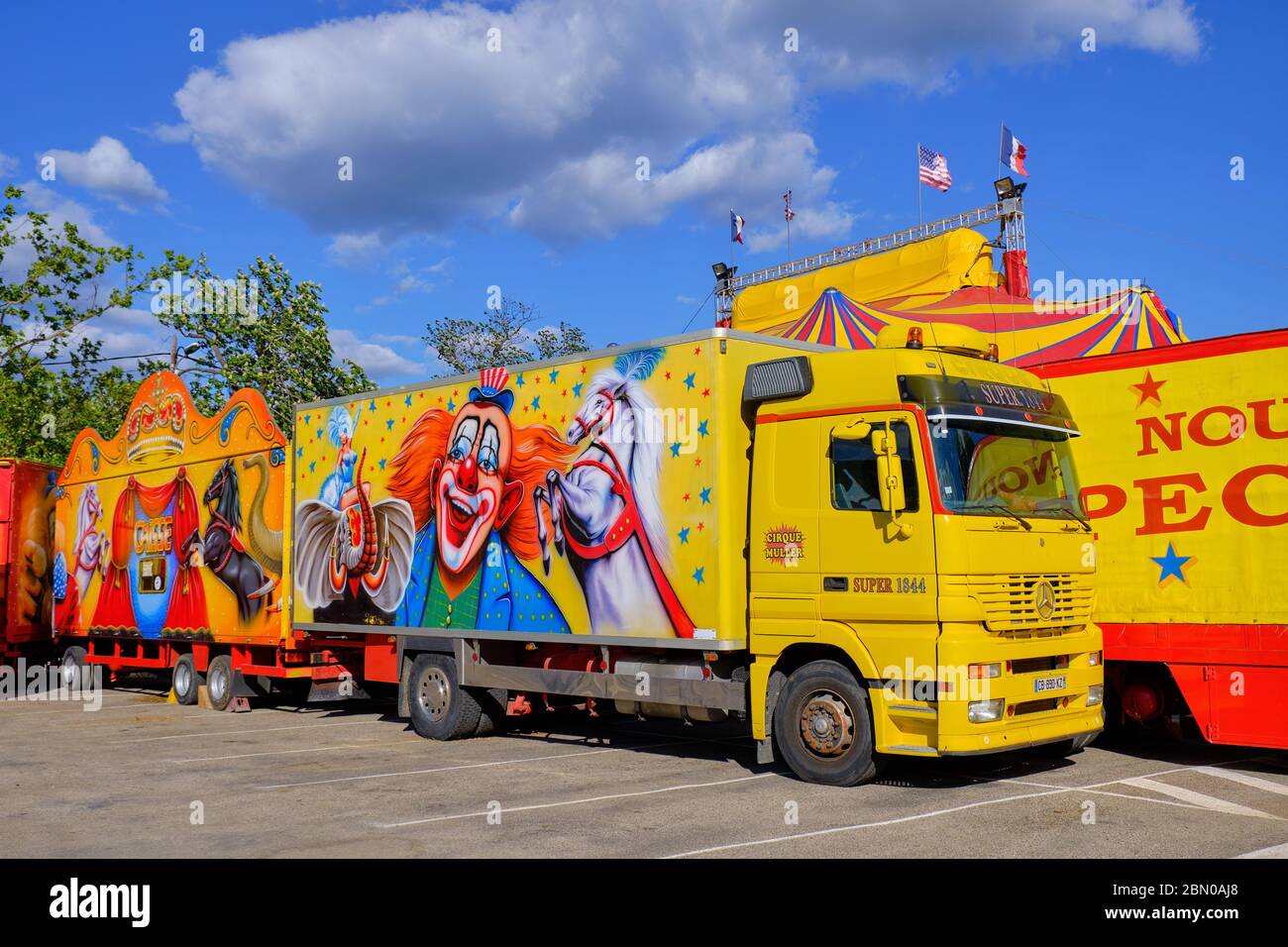 Parcheggiato camion del 'Cirque Muller' in piazza della città, mentre la tenda è in fase di messa in piedi dietro in preparazione per lo spettacolo. Lodeve, Francia, maggio 2019 Foto Stock