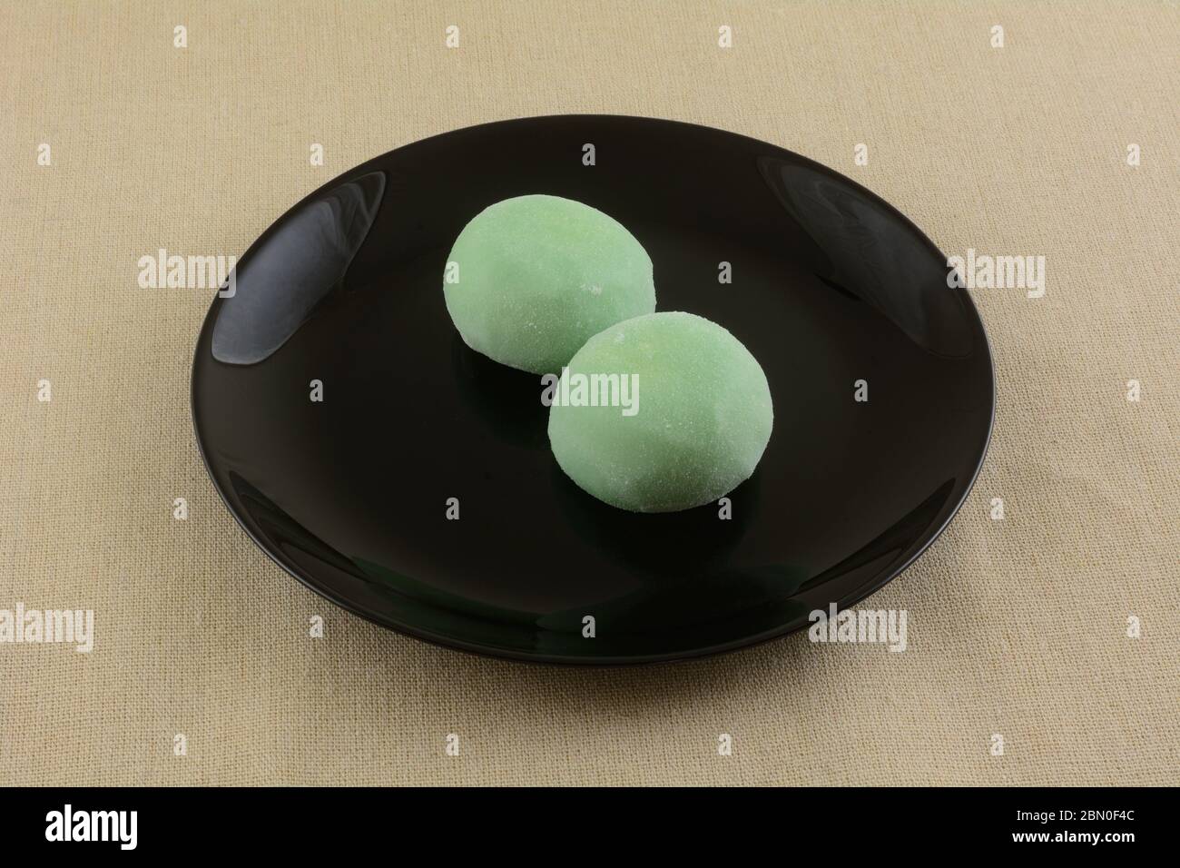 Palle di gelato al tè verde mochi su piatto da dessert nero su tovaglia marrone Foto Stock