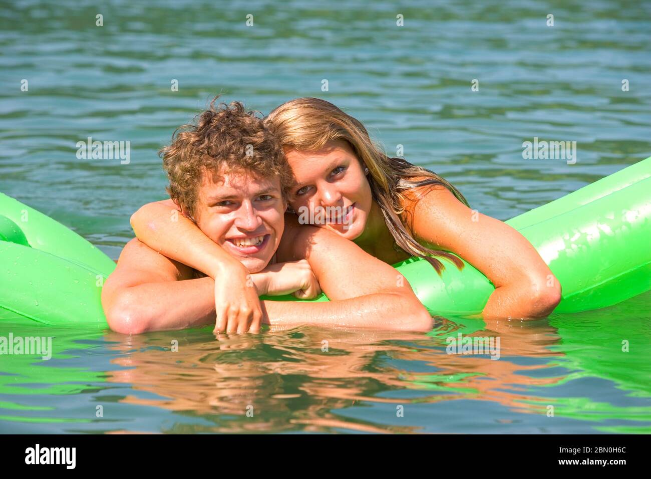 Coppia innamorata sdraiata su un materasso ad aria in acqua, 18 anni, Mondsee, Austria superiore, Austria Foto Stock
