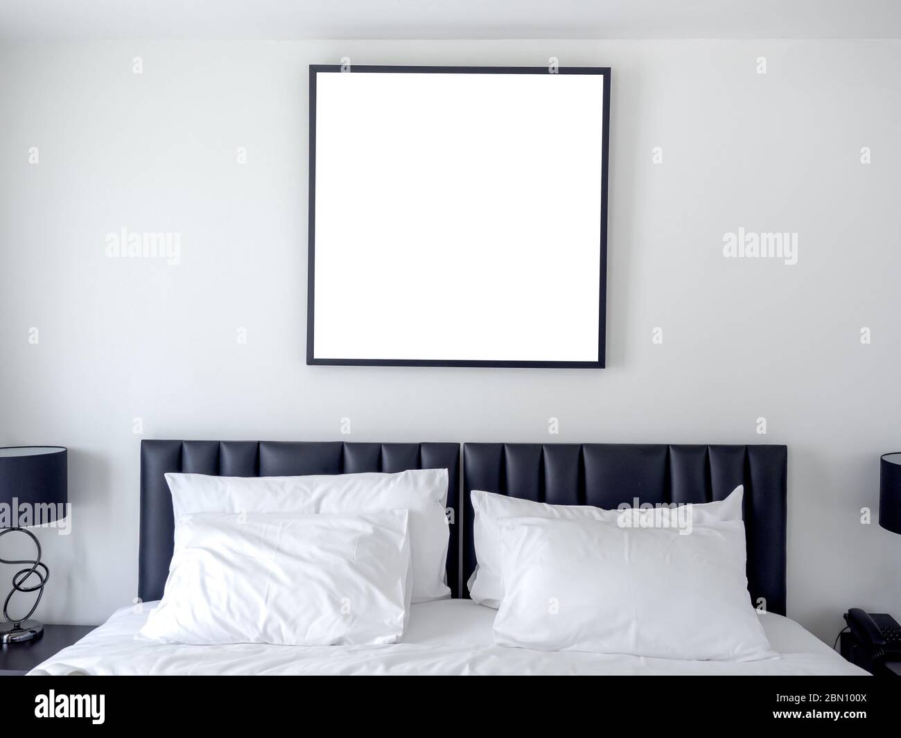 Foto in bianco cornice quadrata mockup su parete bianca sopra il letto con bianchi cuscini puliti in camera da letto. Foto Stock
