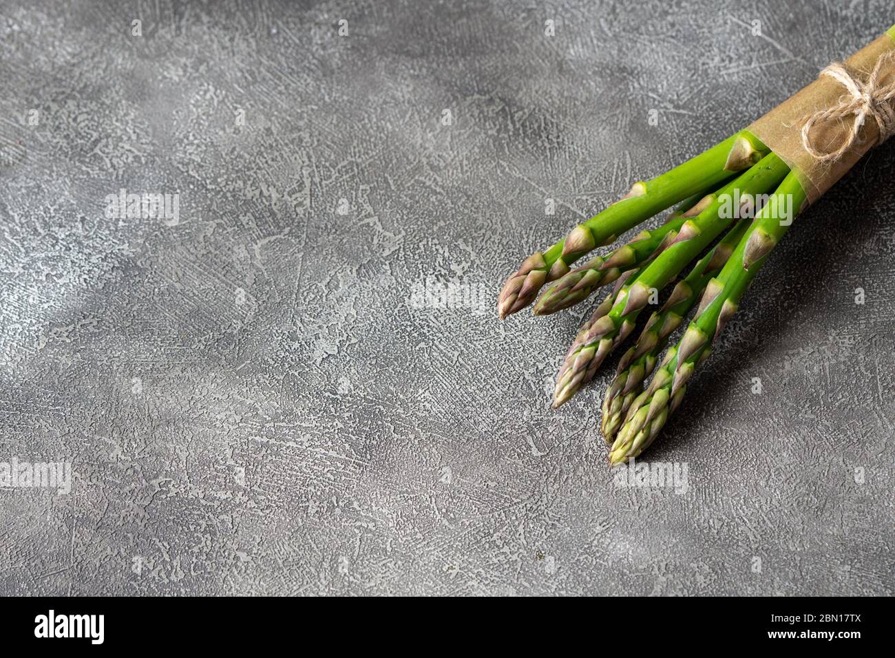 Mazzo di asparagi freschi su sfondo grigio. Spazio di copia. Verdure fresche e sane. Foto Stock