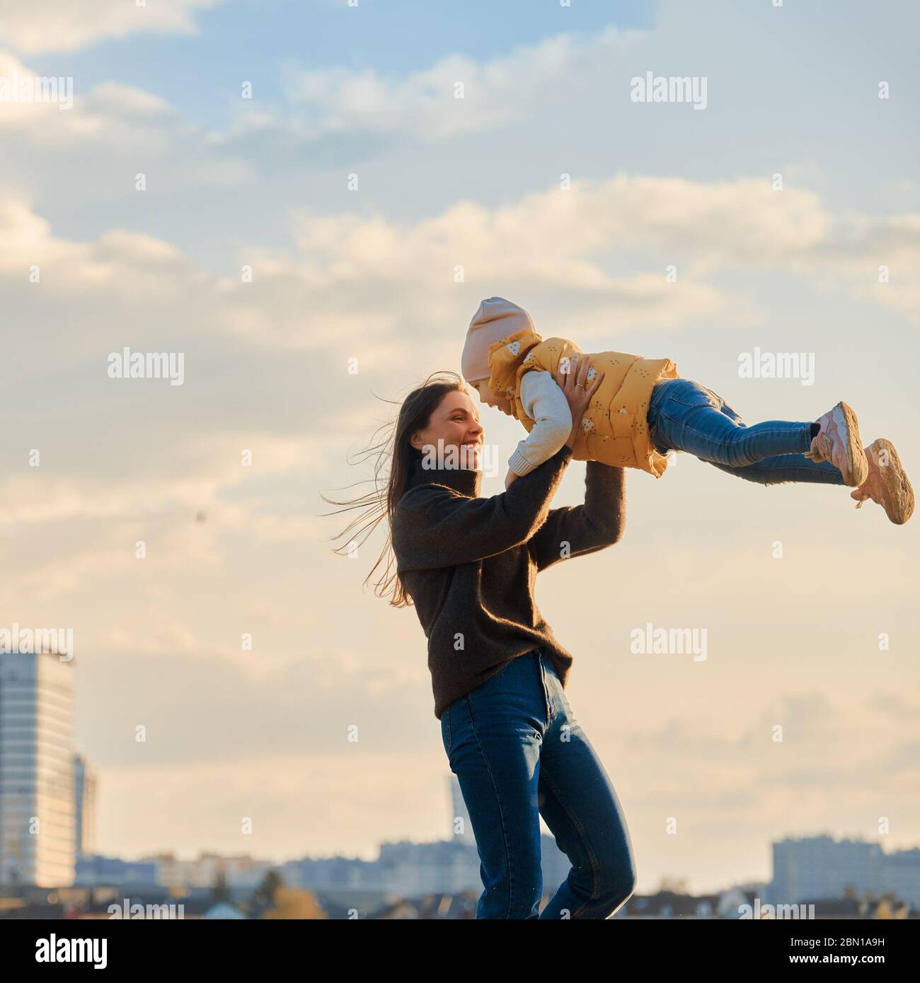 ritratto di mamma con una figlia tra le braccia sullo sfondo del paesaggio urbano Foto Stock