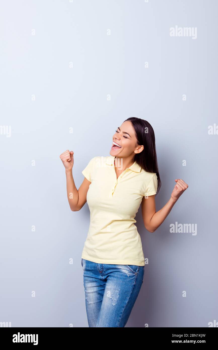 OH sì! Felice stupita giovane mulatto ragazza sta celebrando. È eccitato e con la bocca aperta su fondo chiaro puro, lei è indossando casual giallo Foto Stock