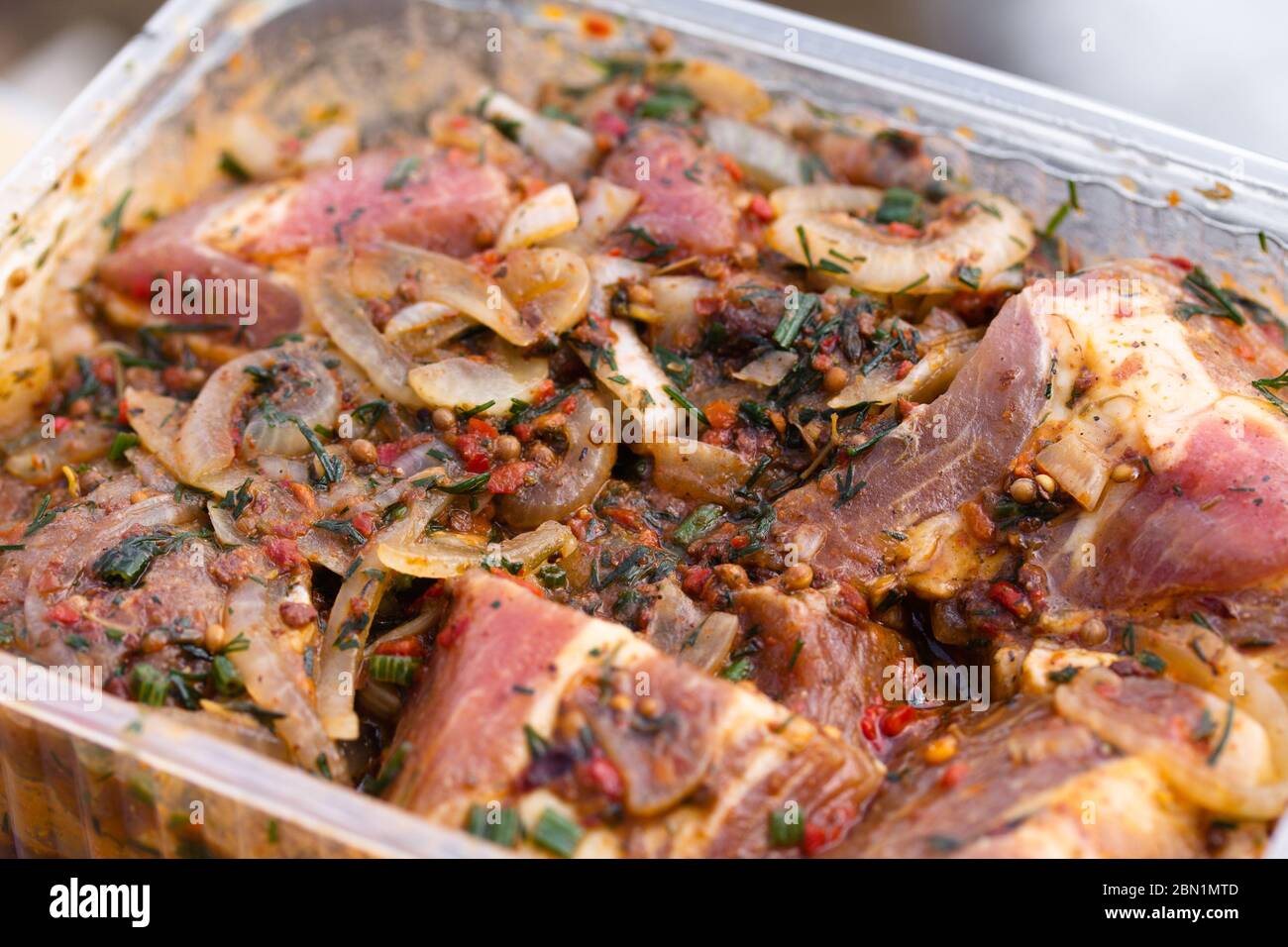 Carne di maiale cruda e succosa marinata in contenitore di plastica. Cibo fresco preparato per barbecue. Cucina estiva all'aperto Foto Stock