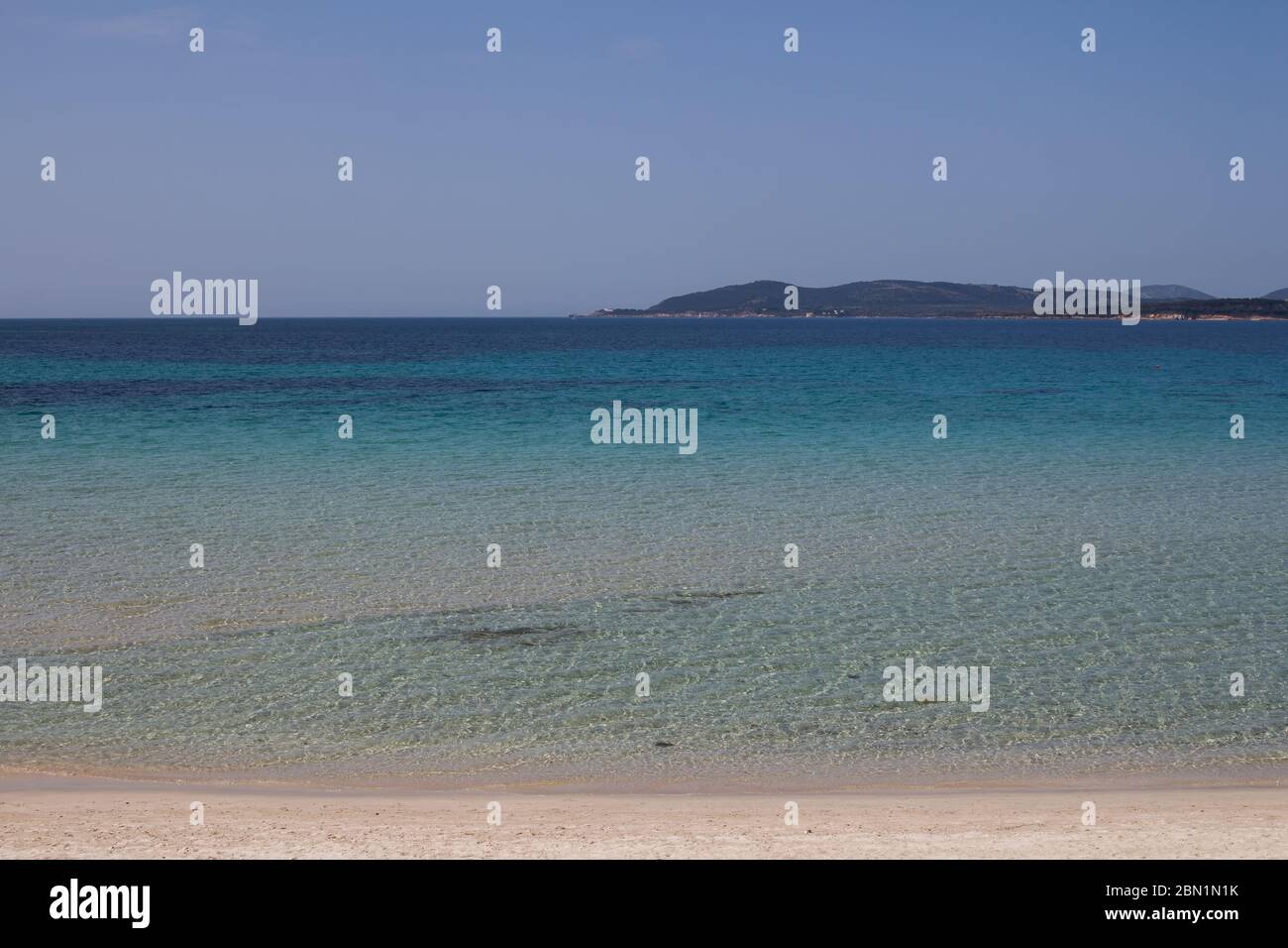 Acque calme del Mediterraneo. Acqua blu e cielo. Montagne all'orizzonte. Giornata primaverile ad Alghero, Sardegna, Italia. Foto Stock