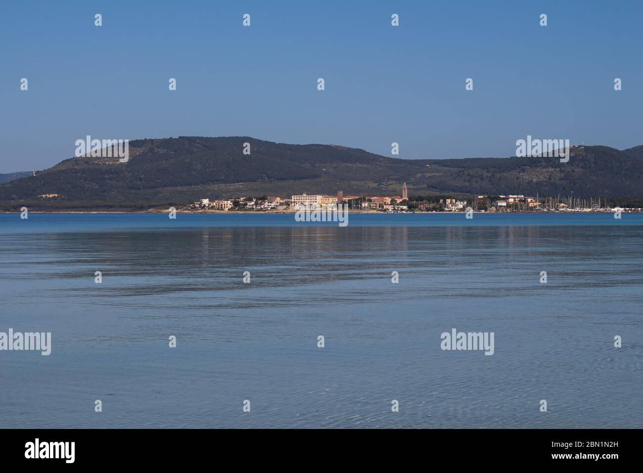 Acque calme del Mediterraneo. Acqua blu e cielo. Montagne all'orizzonte. Giornata primaverile ad Alghero, Sardegna, Italia. Foto Stock