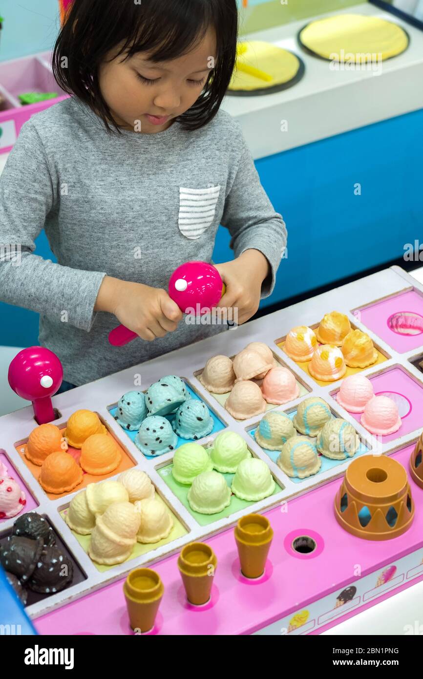 Cute Asian bambino, ruolo del bambino che gioca gelato scoop nel negozio di gelato giocattolo al parco divertimenti interno per bambini. Gioca e impara attività per bambini. Foto Stock
