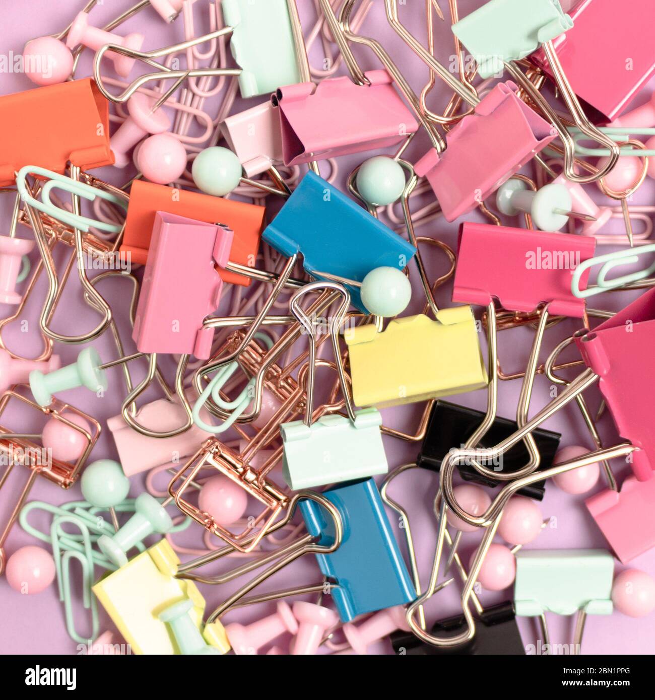Trama composta da graffette e spille su sfondo rosa pastello. Foto Stock