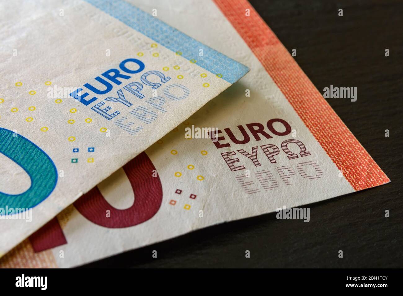 Macrofotografia di euro di parole su due banconote in euro su sfondo nero. Denaro, reddito e spese, stato dell'economia. Primo piano. Foto Stock