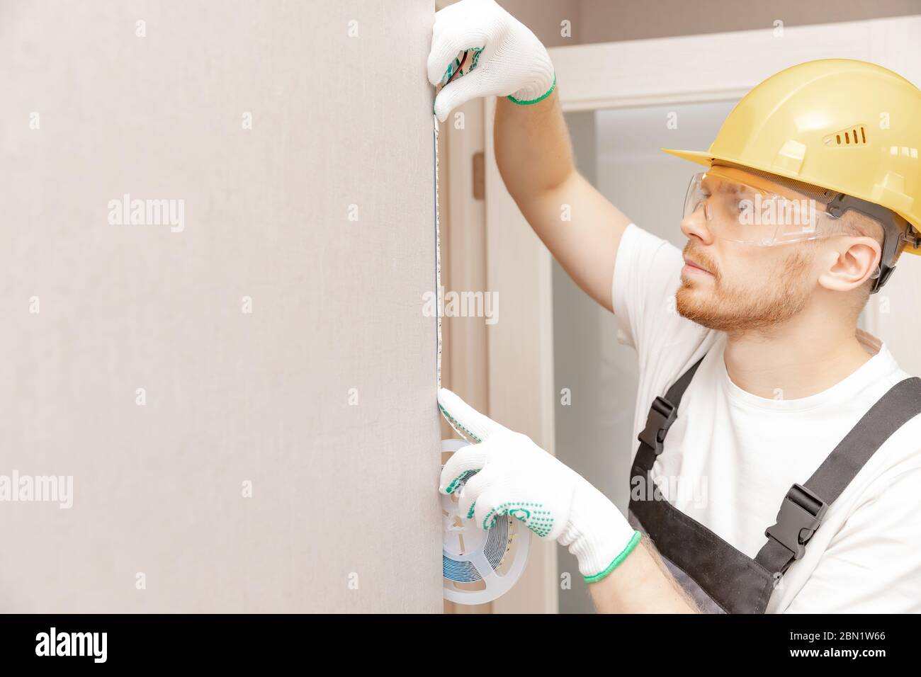 Elettricista che installa il nastro di montaggio striscia LED illuminazione decorativa Foto Stock