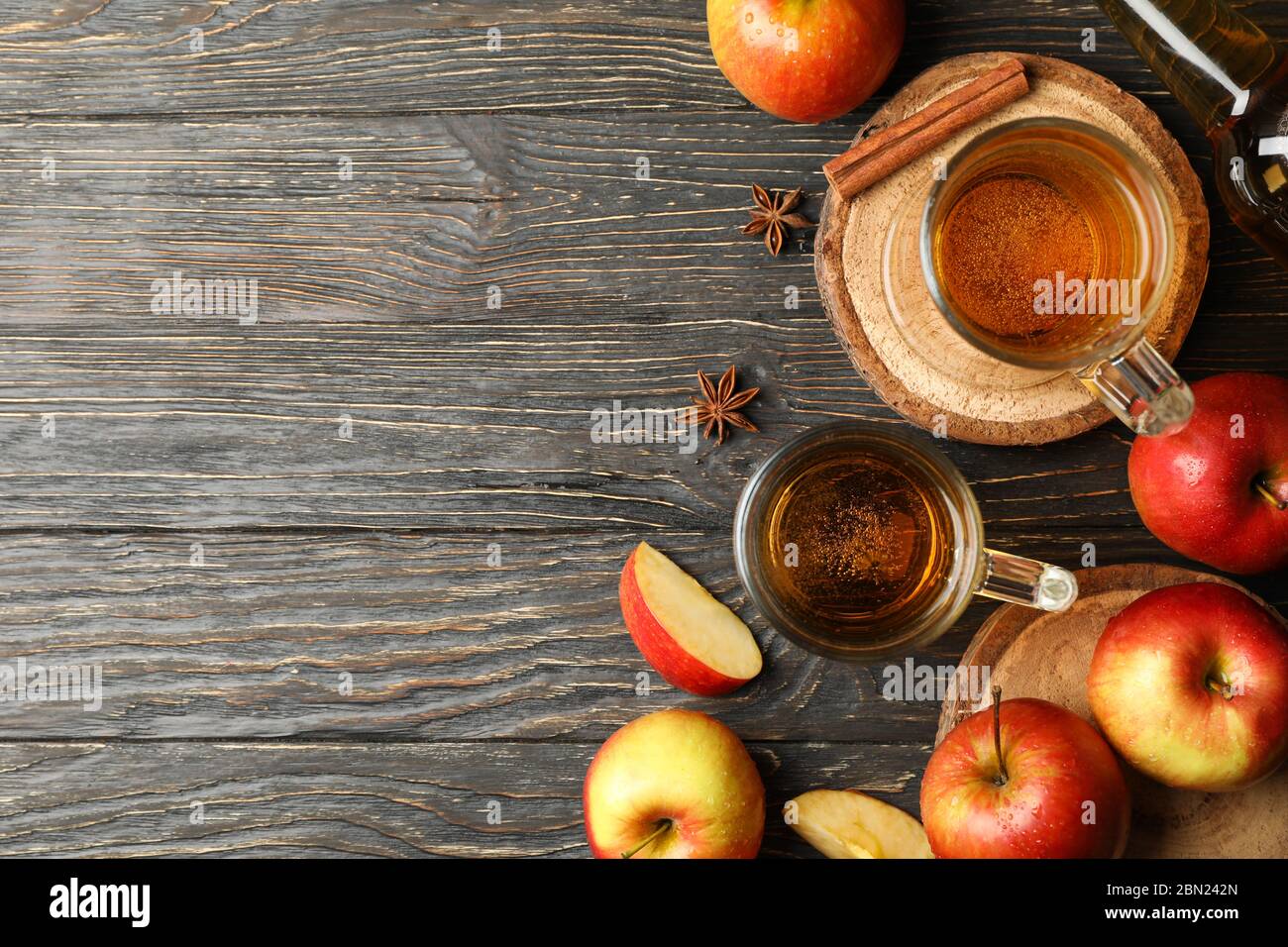 Composizione con sidro, cannella e mele su fondo ligneo Foto Stock