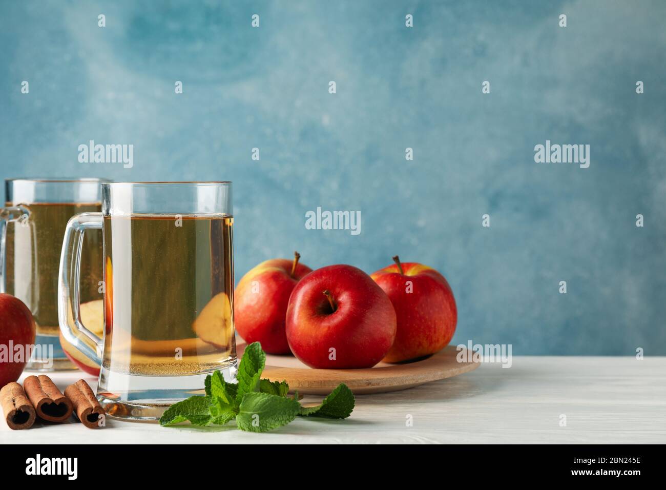 Composizione con sidro, cannella e mele su fondo di legno bianco Foto Stock